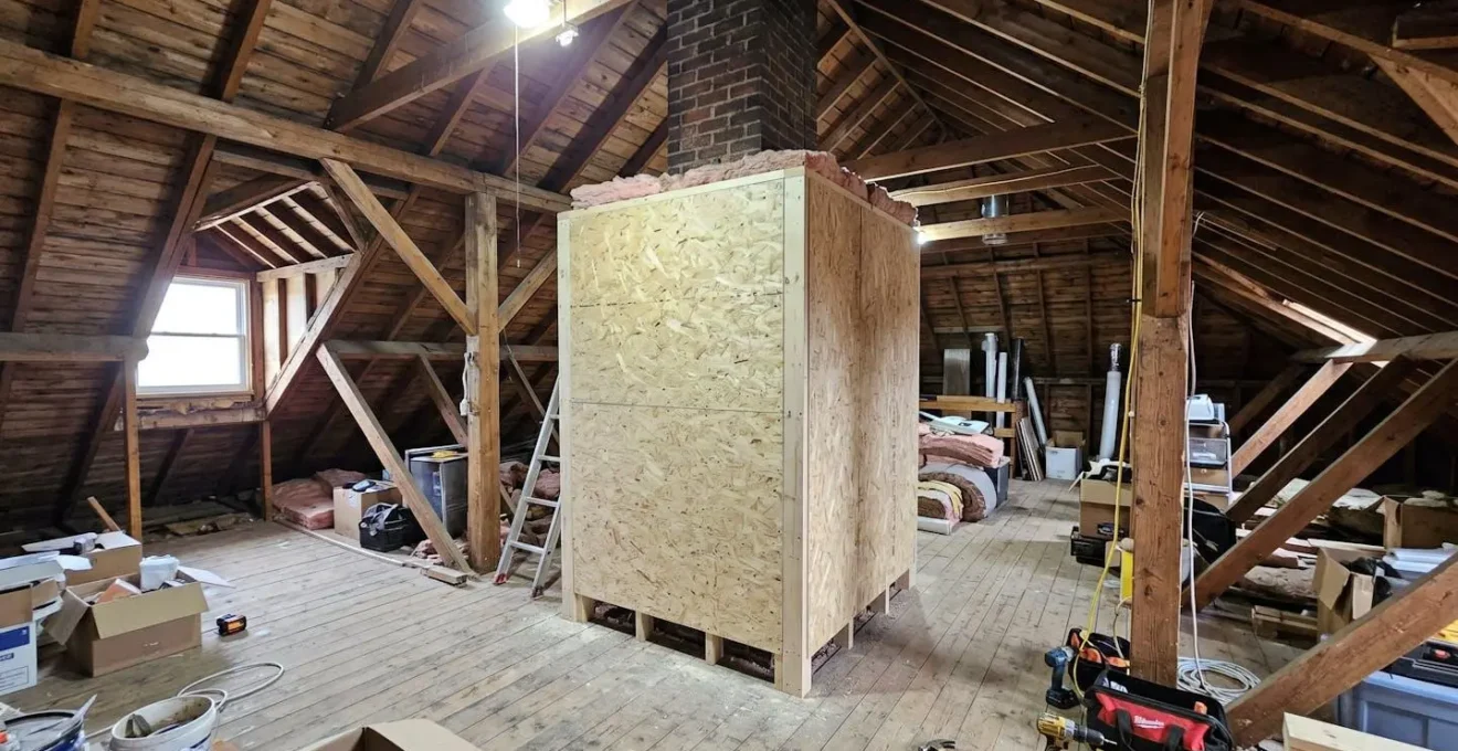 Vue large d'un coffrage de protection installé autour d'un conduit de cheminée dans des combles