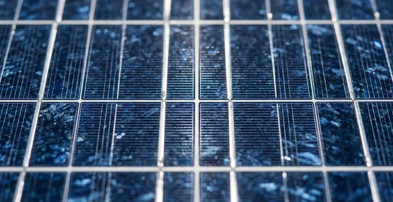 Vue macro de panneaux solaires avec reflets de lumière créant des motifs géométriques